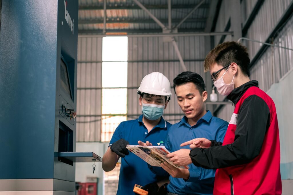 Workers in a warehouse reviewing blueprints, emphasizing teamwork and safety.